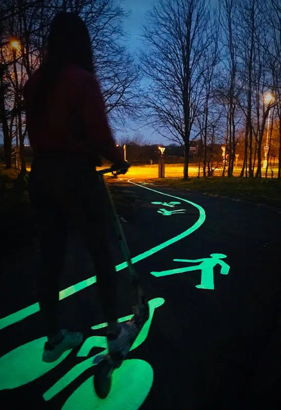 Person on a scooter riding over glowing photoluminescent path markings